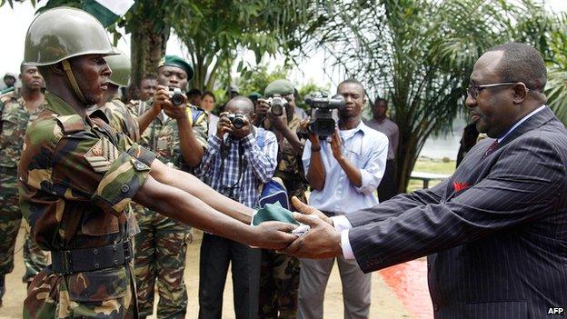 A Nigerian soldier presents a flag after lowering it to Nigerian Justice Minister Bayo Ojo to signify the country's final withdrawal from the Bakassi Peninsula on 14 August 2006