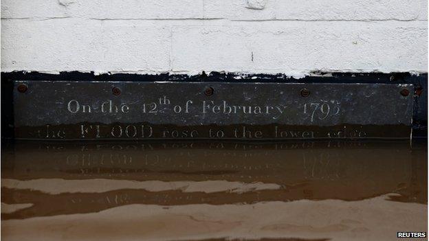 A plaque on a wall above flood water reads "On the 12th of February 1795 the FLOOD rose to the lower edge" in Worester, central England