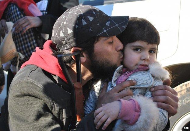 A rebel fighter kisses a little girl goodbye in Homs, 12 February