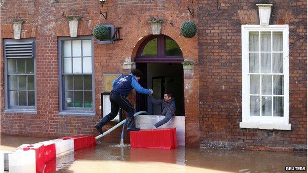 Men climb in to a restaurant surrounded by flood waters in Worcester