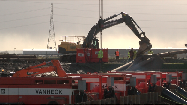 A digger helps install large water pumps