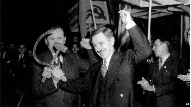 Earl Browder, right, Communist US presidential candidate, crosses a hammer with a sickle held by Charles Krumbein, state secretary of the Communist Party, as they stand before a crowd gathered for the final rally of the campaign at Madison Square Garden in New York City, 2 November 1936