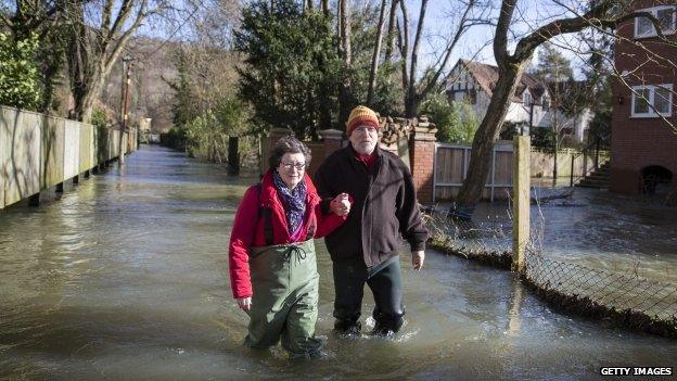 Residents walk along a flooded street in Henley, Oxfordshire