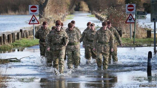 Members of The King's Royal Hussars wade through flood water on Chertsey Meads