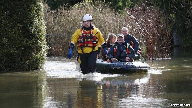 Volunteers from the International Rescue Corps help a couple evacuate from a flooded house in Chertsey