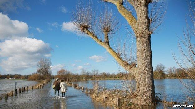 A couple walk through flood water on Chertsey Meads, in Chertsey,