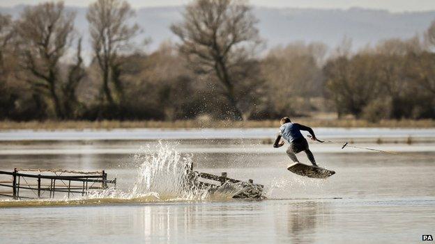 A wakeboarder does a jump in a flooded field