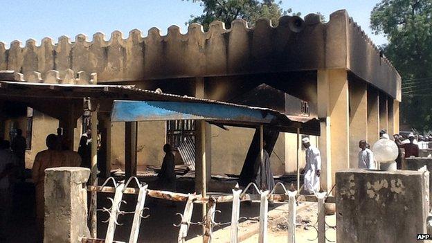 People walk around the damaged mosque in the village of Konduga, in north-eastern Nigeria, on 12 February 2014.