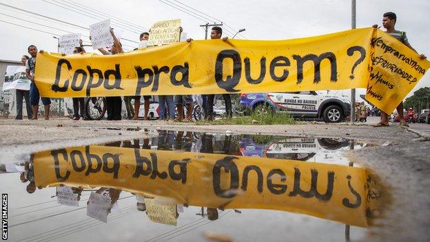 Protestors outside the Amazonia Arena with a banner that reads "World Cup for whom?"