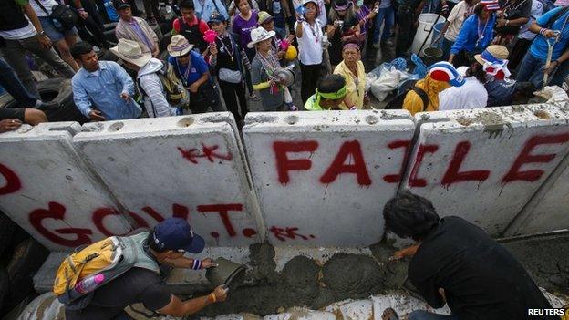 Anti-government protesters pour cement near a concrete wall set up to block a gate of the Government House during a rally in Bangkok, 17 February 2014