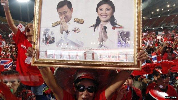 File photo: A red-shirted supporter holds up a pictures of Thailand's Prime Minister Yingluck Shinawatra and her brother Thaksin Shinawatra, during a rally at Rajamangala national stadium in Bangkok, 19 November 2013