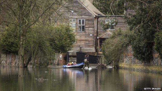 A woman uses a dinghy to transport her children from their flooded home in Hurley, Berkshire