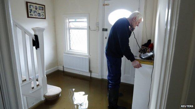 Michael Simmonds speaks on the phone in his flooded home at Egham