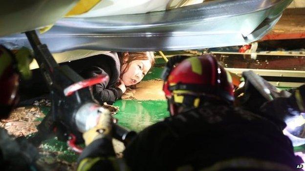 A woman trapped in the rubble of a collapsed resort building waits to be rescued