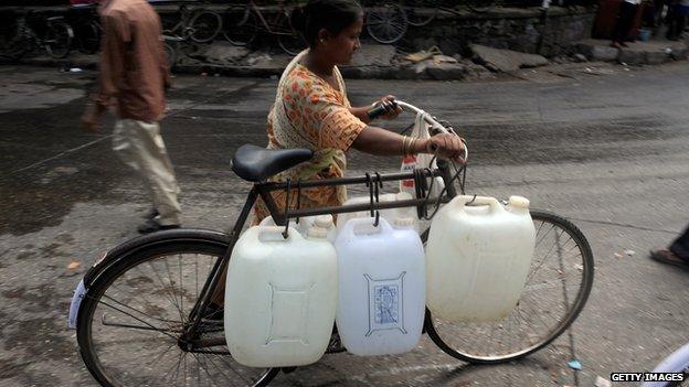 woman transporting water bottles on a bicycle, India