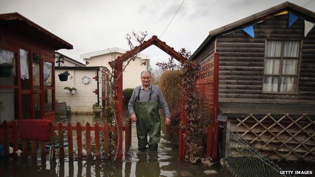 A man walking across a flooded garden in Chertsey, Surrey