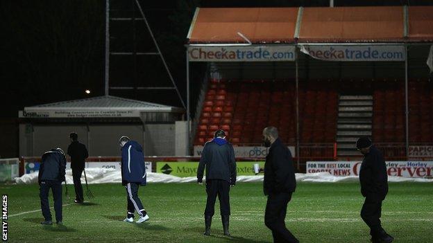 Crawley groundstaff inspect the pitch after the postponement