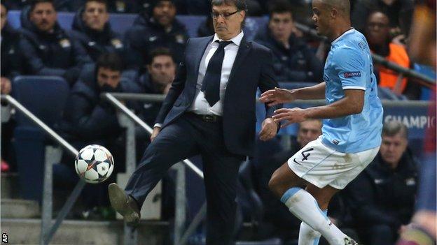 Barcelona head coach Gerardo Martino beats Manchester City defender Vincent Kompany to the ball