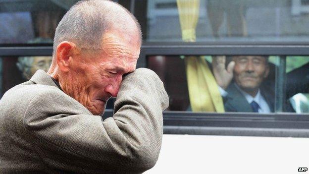 This file photo taken on 31 October 2010 shows an elderly South Korean man wiping his tears as a North Korean relative (in the bus) waves to say good-bye after a luncheon during a separated family reunion meeting