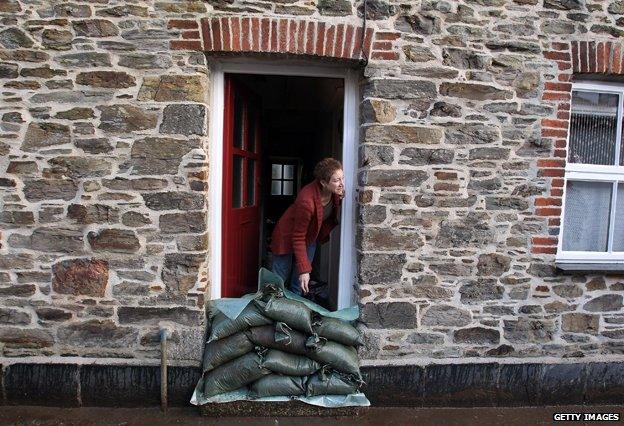 Resident looks out of front door of flooded house