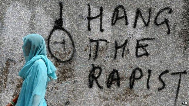 In this photograph taken on April 22, 2013, an Indian pedestrian walks past graffiti against rape written on a wall in New Delhi.