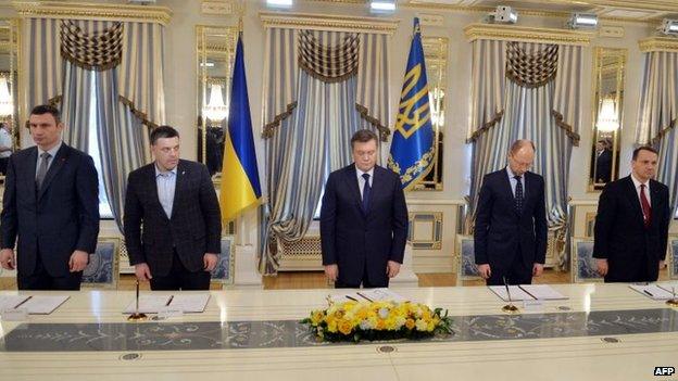 Ukrainian President Yanukovych (centre), opposition leaders and Polish Foreign Minister Radoslaw Sikorski sign the agreement