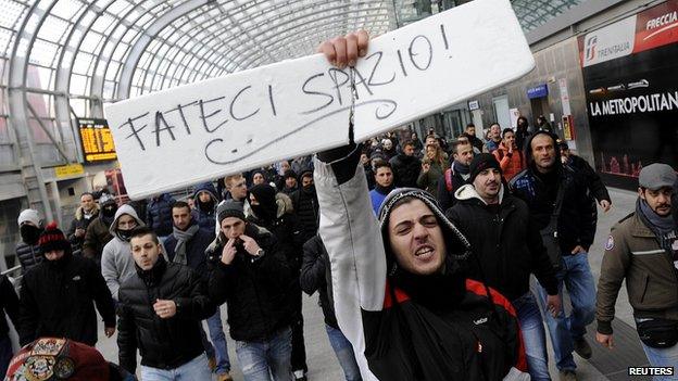 A protester at Turin train station holds a sign reading "Make room for us" during protests against targets including banks and the tax collection agency, Dec 2013