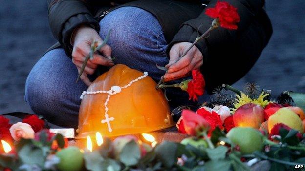 Woman places a flower on the helmet of a dead protester in Kiev (21 February 2014)