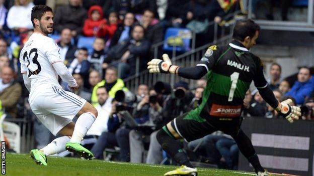 Real Madrid's midfielder Isco (left) scores past Elche's goalkeeper Manu Herrera