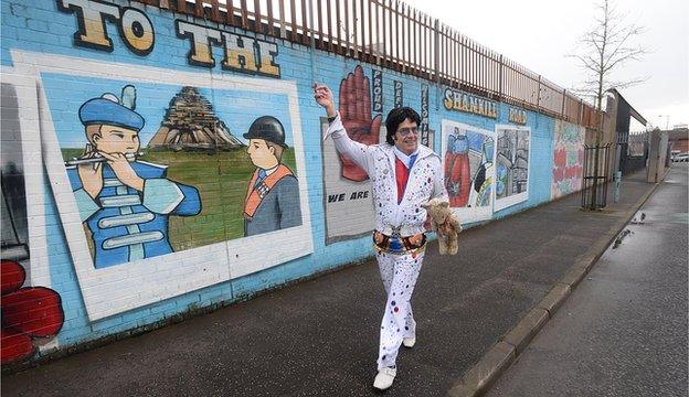 The Reverend Elvis, also known as Andy Kelso, waves from the peace line in west Belfast