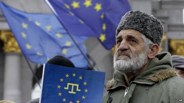 A Crimean Tatar protester in Kiev hold a flag with the Crimean Tatar symbol on an EU flag