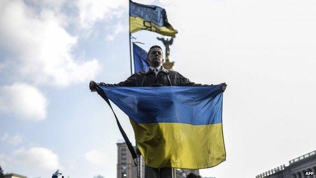 A man holds a Ukrainian flag as he stands on Kiev's Independence Square