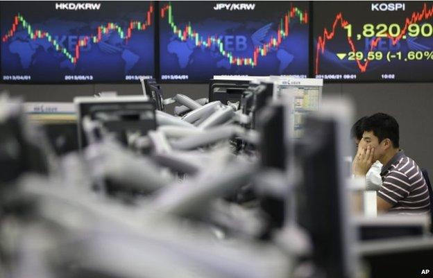 A currency trader watches the computer monitors at the foreign exchange dealing room of the Korea Exchange Bank headquarters in Seoul, Friday, June 21, 2013