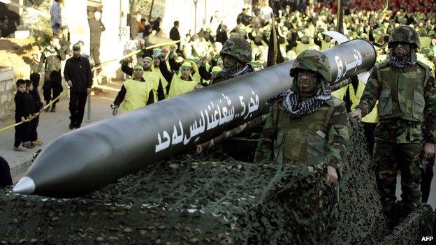 Hezbollah fighters ride on a vehicle carrying a Fajr 5 missile during a parade in the Lebanese town of Nabatiyeh on 28 November 2012