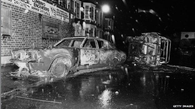 Cars left overturned and burned-out in the street after rioting on the Broadwater Farm housing estate