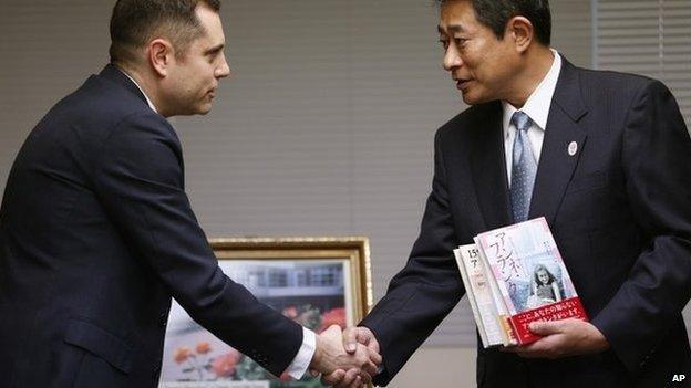 Israeli Embassy to Japan representative Peleg Lewi, left, shakes hands with Suginami Ward Mayor Ryo Tanaka as he hands over Anne Frank-related books to public libraries at the Suginami Ward Office in Tokyo Thursday, Feb. 27, 2014