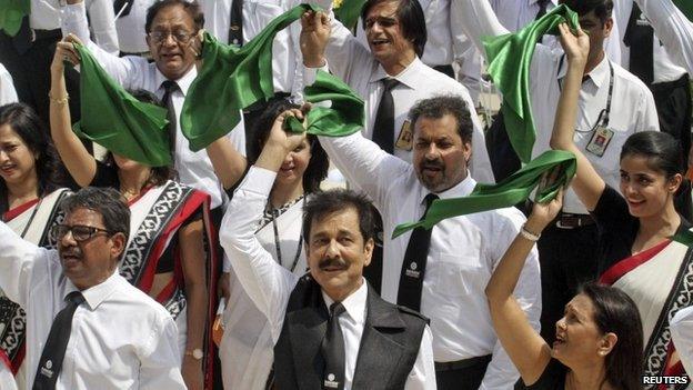 Subrata Roy (C, front) waves a green cloth with his employees after singing India's national anthem on May 6, 2013