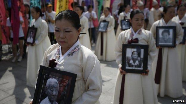 Participants carry the portraits of Korean women who were made sex slaves by the Japanese military during World War Two, during a requiem ceremony for former comfort woman Lee Yong-nyeo in central Seoul, South Korea, 14 August 2013