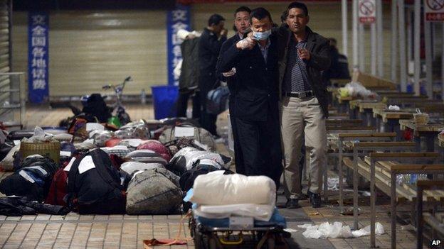 A worker wearing a mask helps the relative of a knife attack victim look through unclaimed luggage after the attack at the Kunming Railway Station in Kunming, Yunnan province, China 2 March 2014