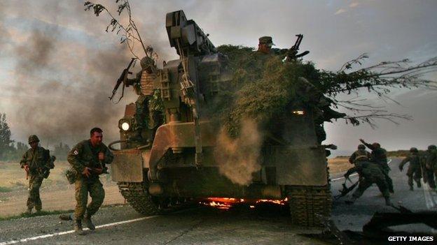 Georgian soldiers escape their burning armoured vehicle on the road during the conflict with Russia in 2008