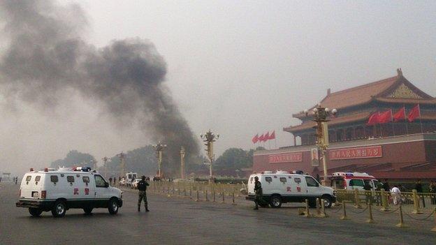 This file photo taken on 28 October 2013 shows police cars blocking off the roads leading into Tiananmen Square as smoke rises into the air after a vehicle loaded with petrol crashed in front of Tiananmen Gate in Beijing