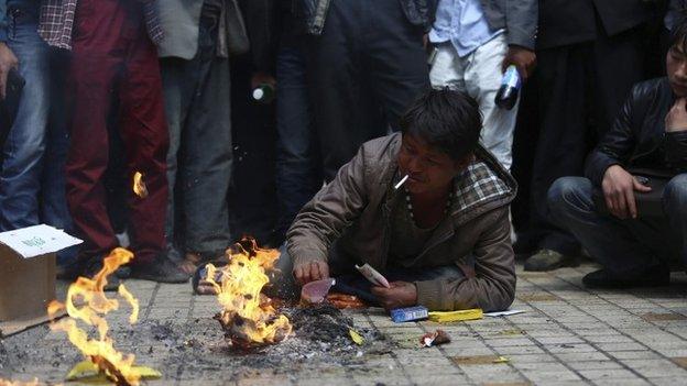 Man, whose relative was killed in a knife attack, lies on the floor as he burns offerings at Kunming railway station in Kunming