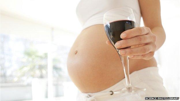 A pregnant woman holding a glass of wine