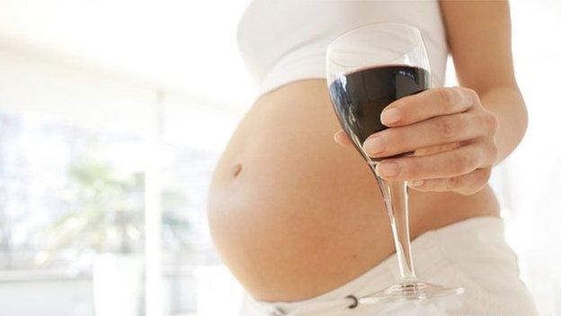 A pregnant woman holding a glass of wine