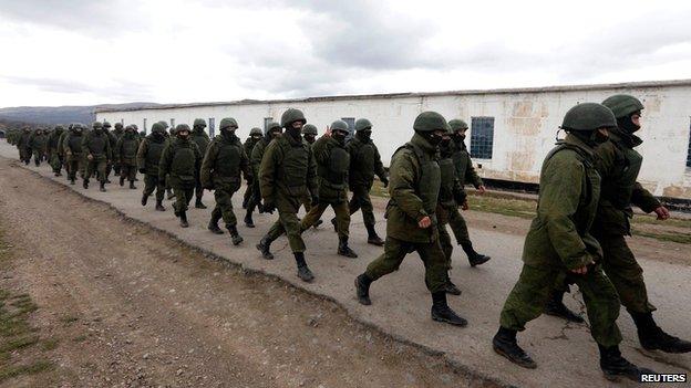 Uniformed men, believed to be Russian servicemen, march outside a Ukrainian military base near the Crimean capital Simferopol on 5 March 2014