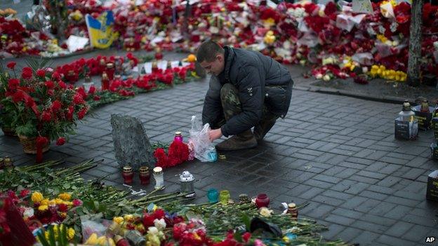 Man lights a candle at a memorial for the protesters who died in clashes with police in Kiev, on 5 March 2014