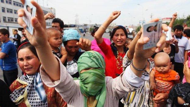 An Uighur woman holds her relatives' ID cards who are are currently detained, as she and others protests on a street on 7 July 2009 in Urumqi, the capital of Xinjiang