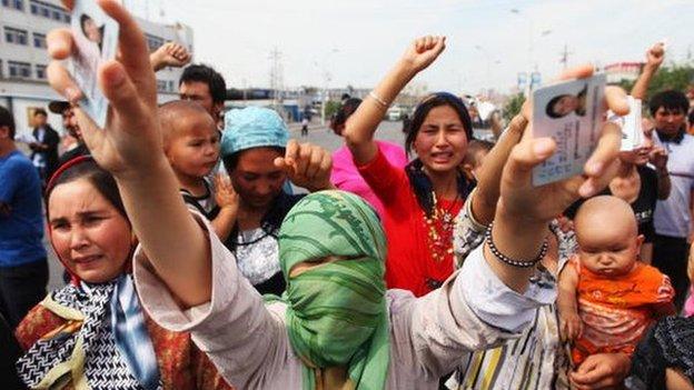 An Uighur woman holds her relatives' ID cards who are are currently detained, as she and others protests on a street on 7 July 2009 in Urumqi, the capital of Xinjiang