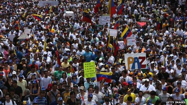 A protester carries a sign reading Peace as thousands of protesters march in an anti-government demonstration on 2 March, 2014, in Caracas