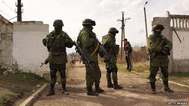 Russian paramilitaries stand guard outside of a Ukrainian military base in the town of Perevevalne near the Crimean city of Simferopol, 6 March